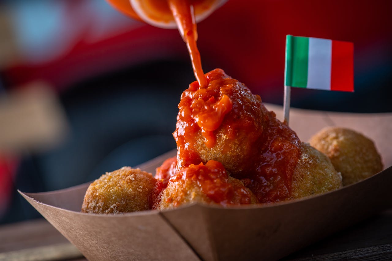 hero-homepage Close-up of Italian arancini drizzled with rich tomato sauce and an Italian flag.